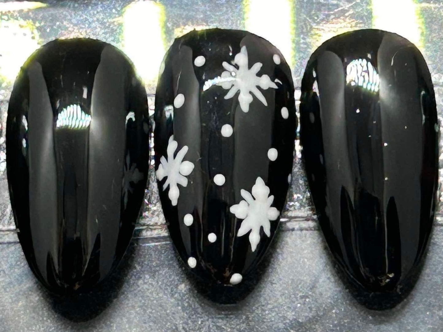 A festive set of glossy gel press-on nails featuring Christmas trees, snowflakes, and red gift bows with rhinestone accents. Displayed in a clear case, the nails come in various sizes and shapes, perfect for holiday glam.