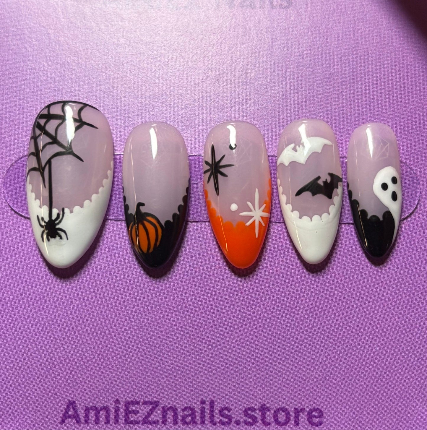 Set of Halloween-themed false nails in a clear case with a purple background, featuring the brand 'AmieEZnails'.