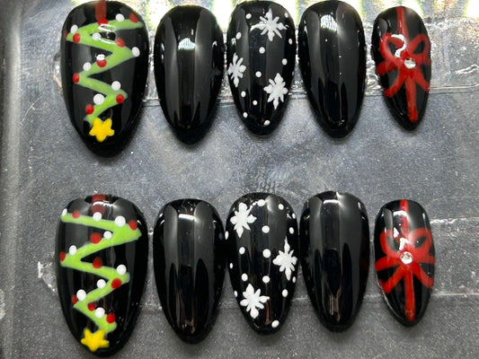 A festive set of glossy gel press-on nails featuring Christmas trees, snowflakes, and red gift bows with rhinestone accents. Displayed in a clear case, the nails come in various sizes and shapes, perfect for holiday glam.